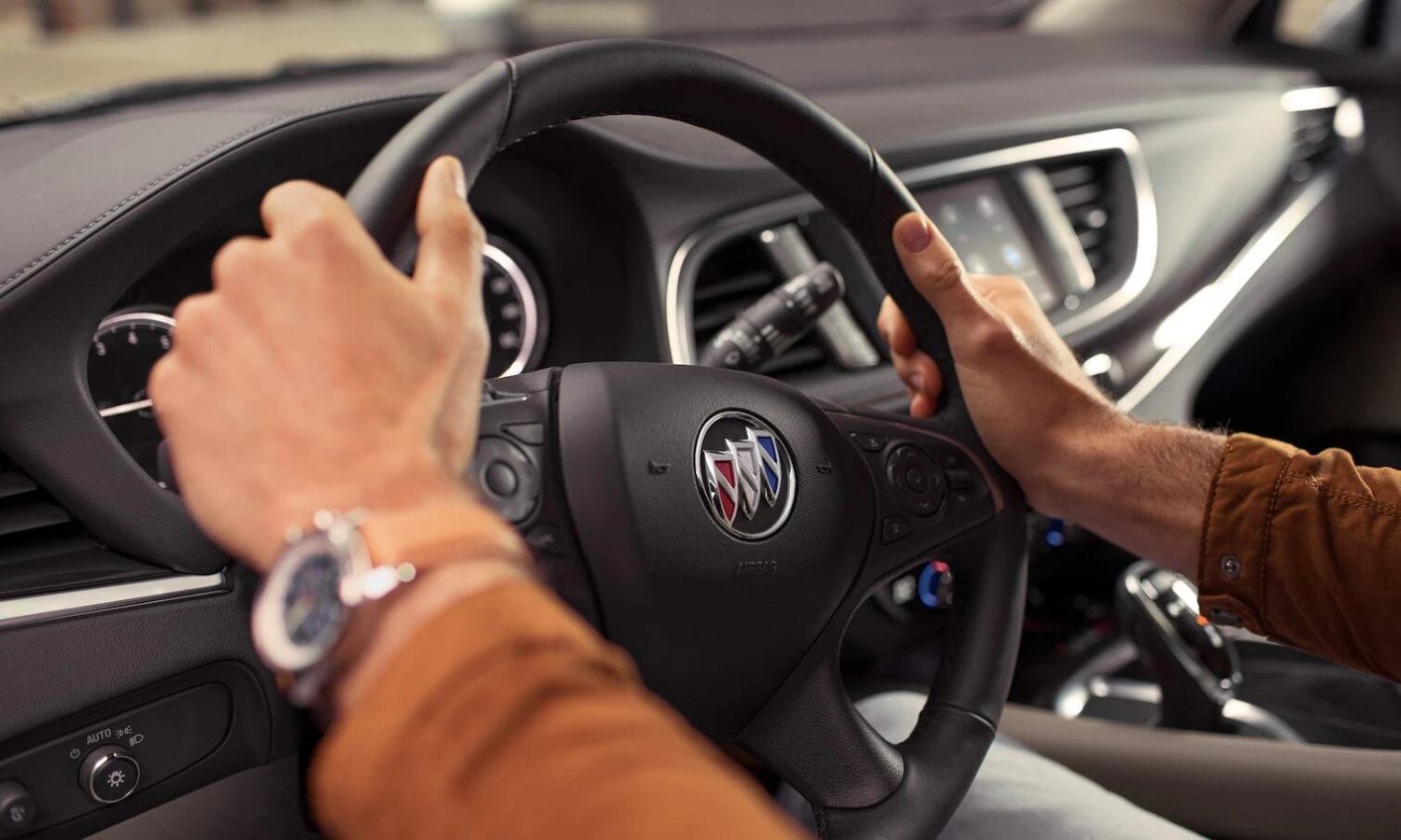 Driver's hands on the steering wheel of a 2022 Buick Enclave SUV