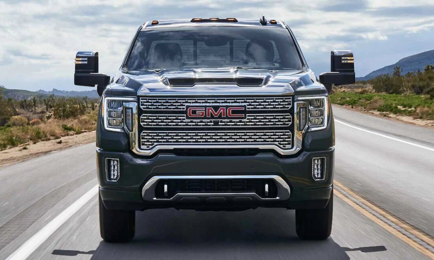 Close up view of the front of a 2022 GMC Sierra 2500HD Denali luxury truck driving toward the camera lens