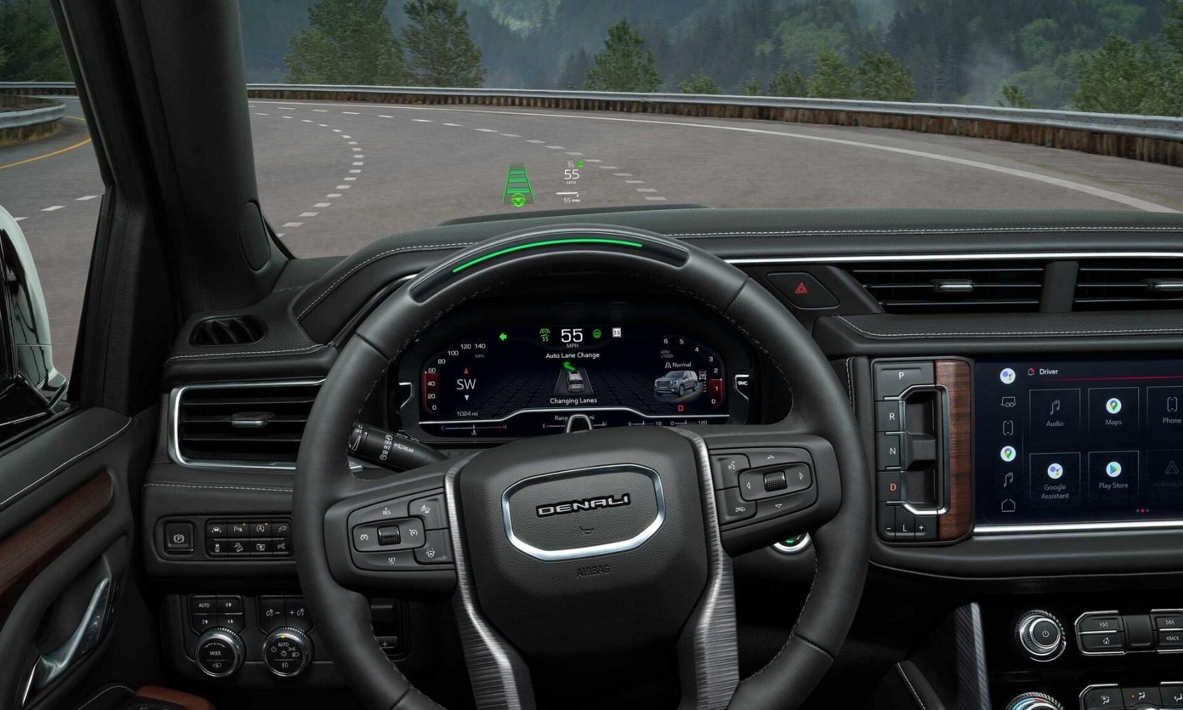Driver eye view of the front dashboard inside the 2023 GMC Yukon showing safety technologies such as the head up display, active GM Super Cruise, and auto lane change on the interactive instrument panel