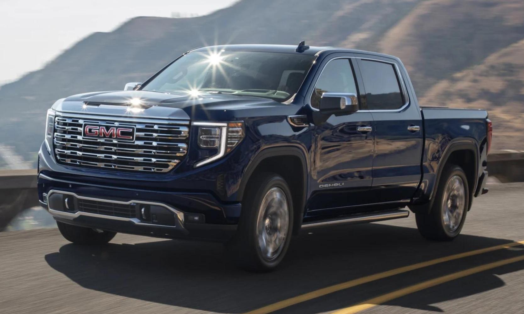 New 2023 GMC Sierra 1500 Denali in blue exterior color driving down a cliffside highway