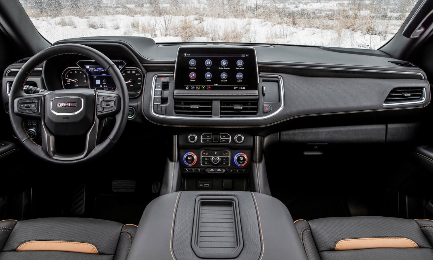 Backseat view of the front interior cabin inside the 2022 GMC Yukon AT4 showing the large infotainment system, center console, and unique AT4 interior colors and stitching
