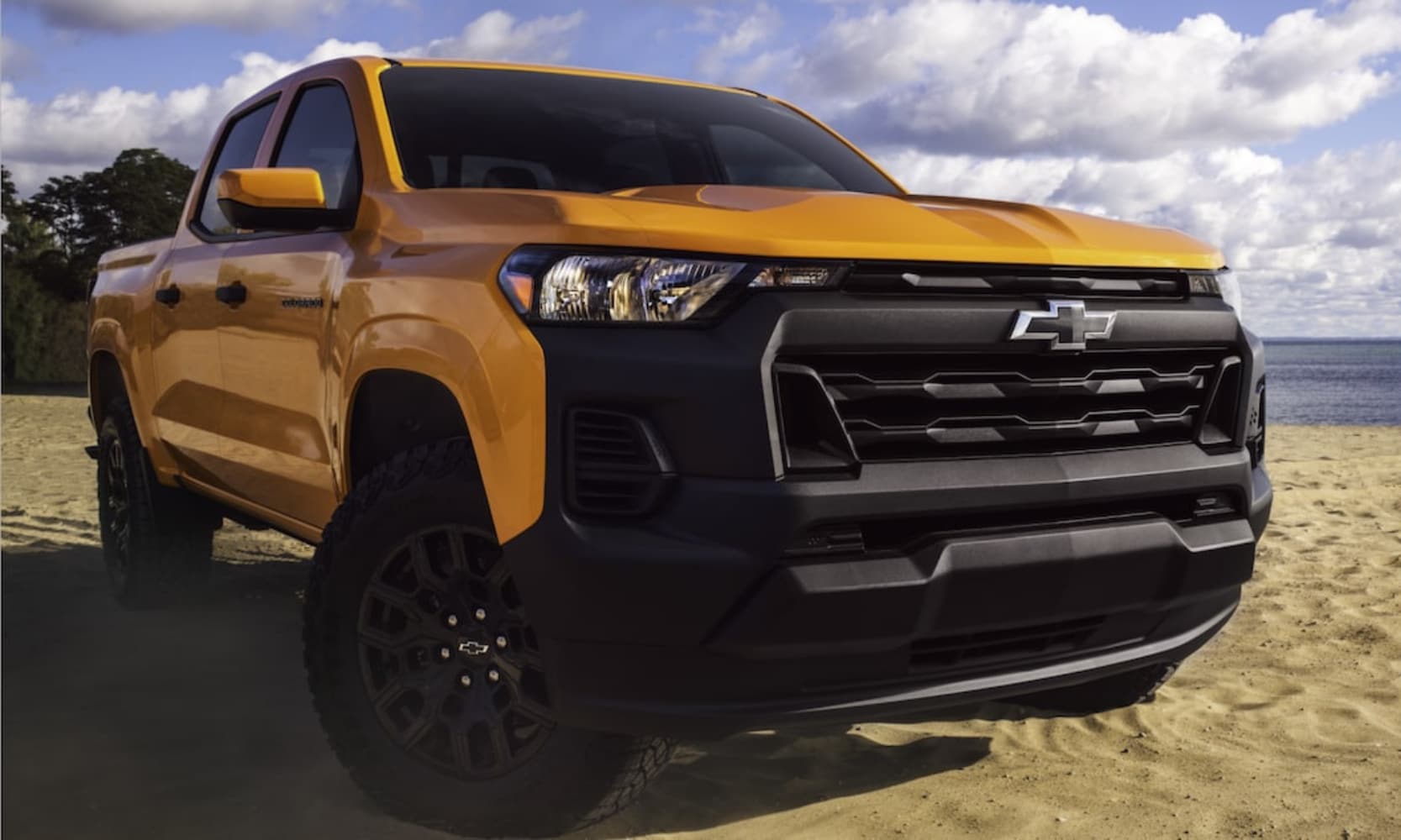 Close-up front exterior image of a yellow 2026 Chevy Colorado WT parked on a beach