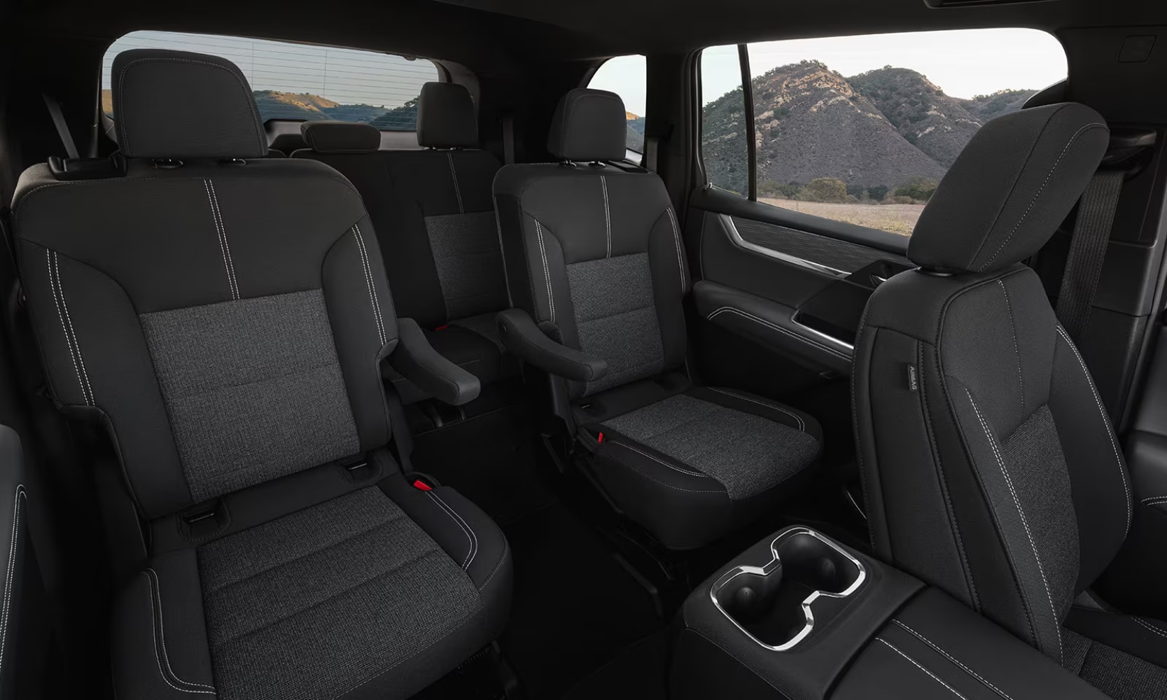 Interior image of a 2026 GMC Acadia dark gray three-row seating and mountain window views