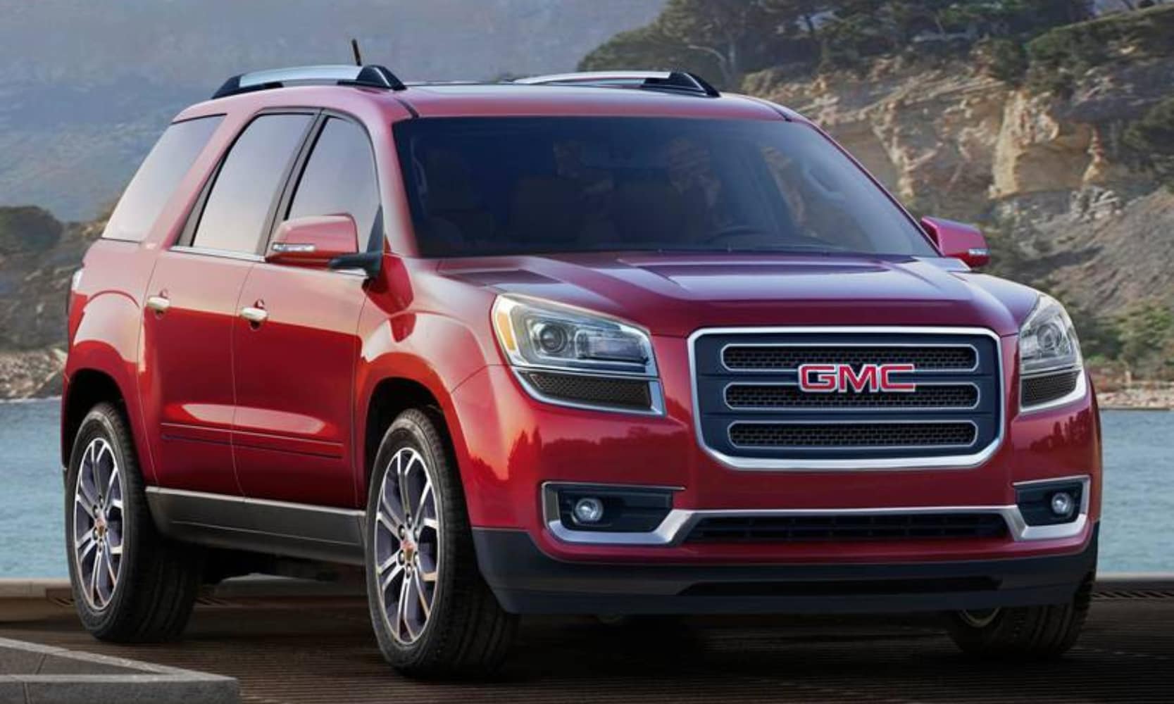 Exterior front image of a red 2016 GMC Acadia SLT-2 parked in front of a waterfront mountain