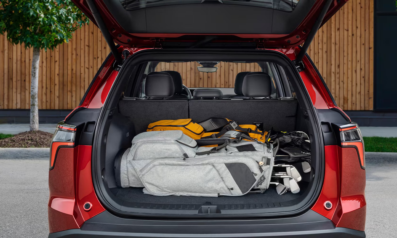 Exterior image of a red 2026 Chevrolet Equinox opened trunk with golf gear inside