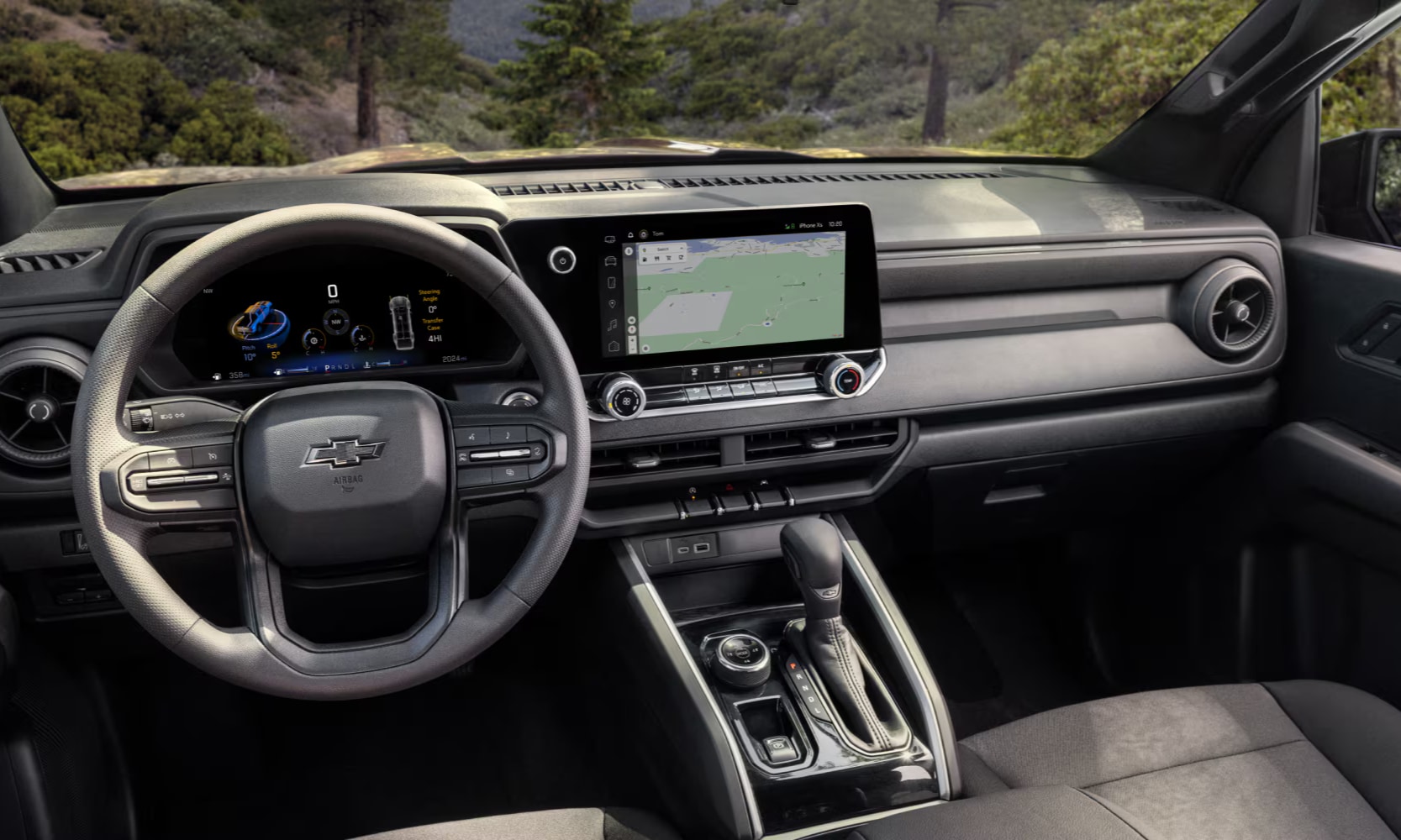 Interior image of a 2026 Chevy Colorado front row area and dashboard with forest windshield views