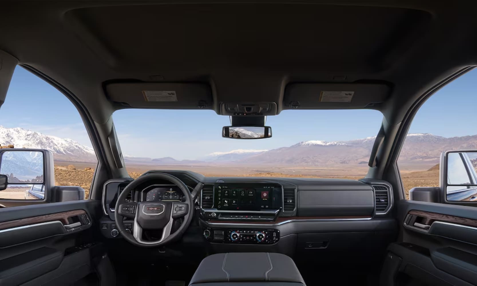 Interior image of a 2025 GMC Sierra 2500 HD front seat area and dashboard with mountain landscape views from the windshield