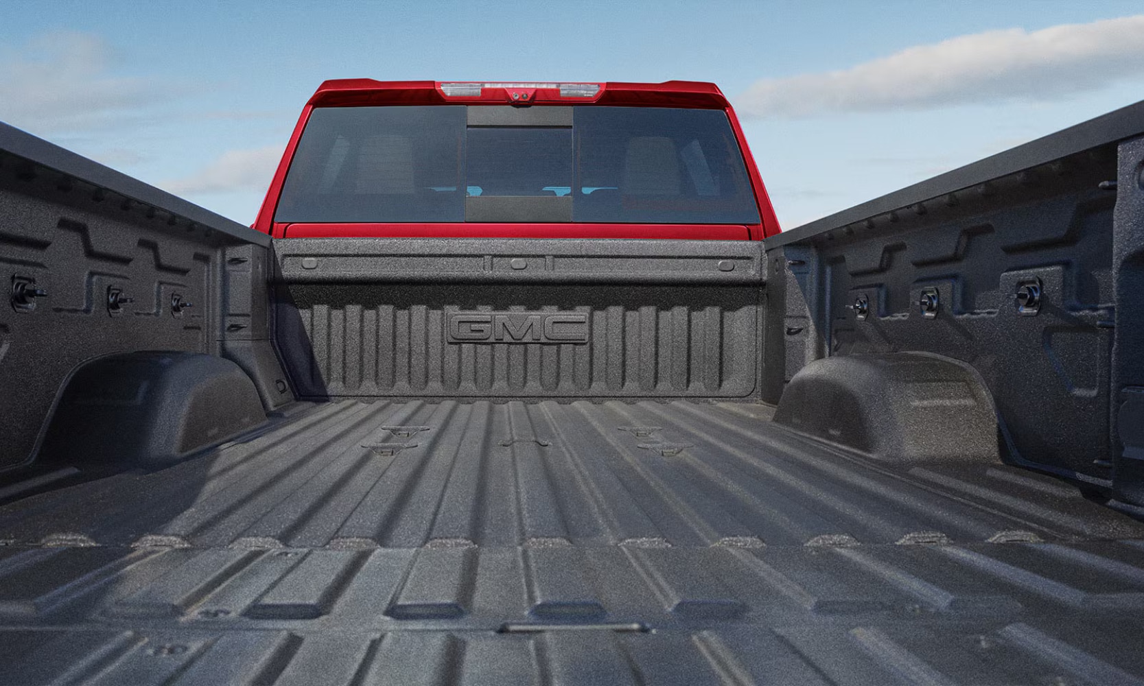 Close-up image of a red 2026 GMC Sierra HD cargo bed with it opened