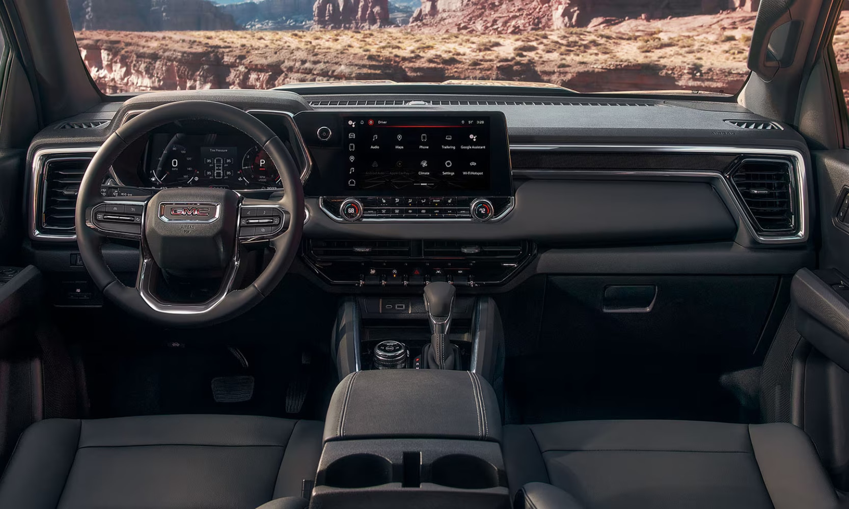 Interior image of a 2026 GMC Canyon Elevation front seating area with rocky mountainous views in the windshield
