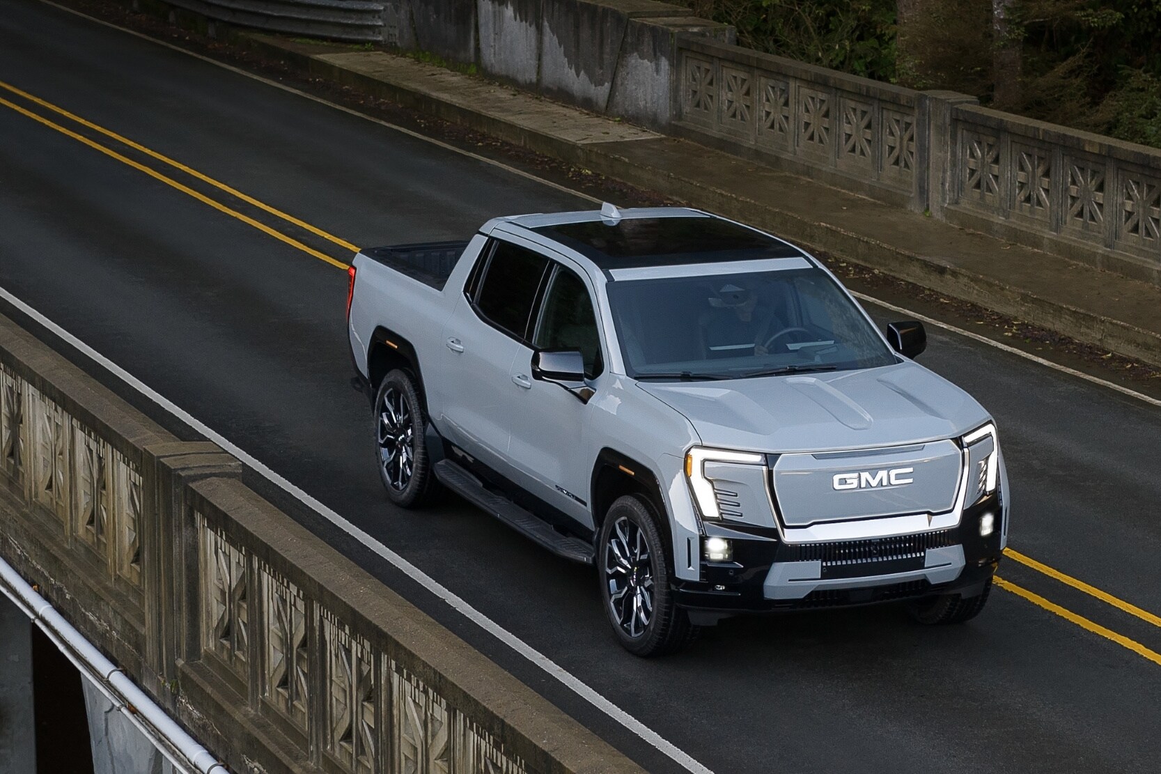 aerial view of a 2025 GMC Sierra EV Denali driving across a large bridge coming out of a tunnel