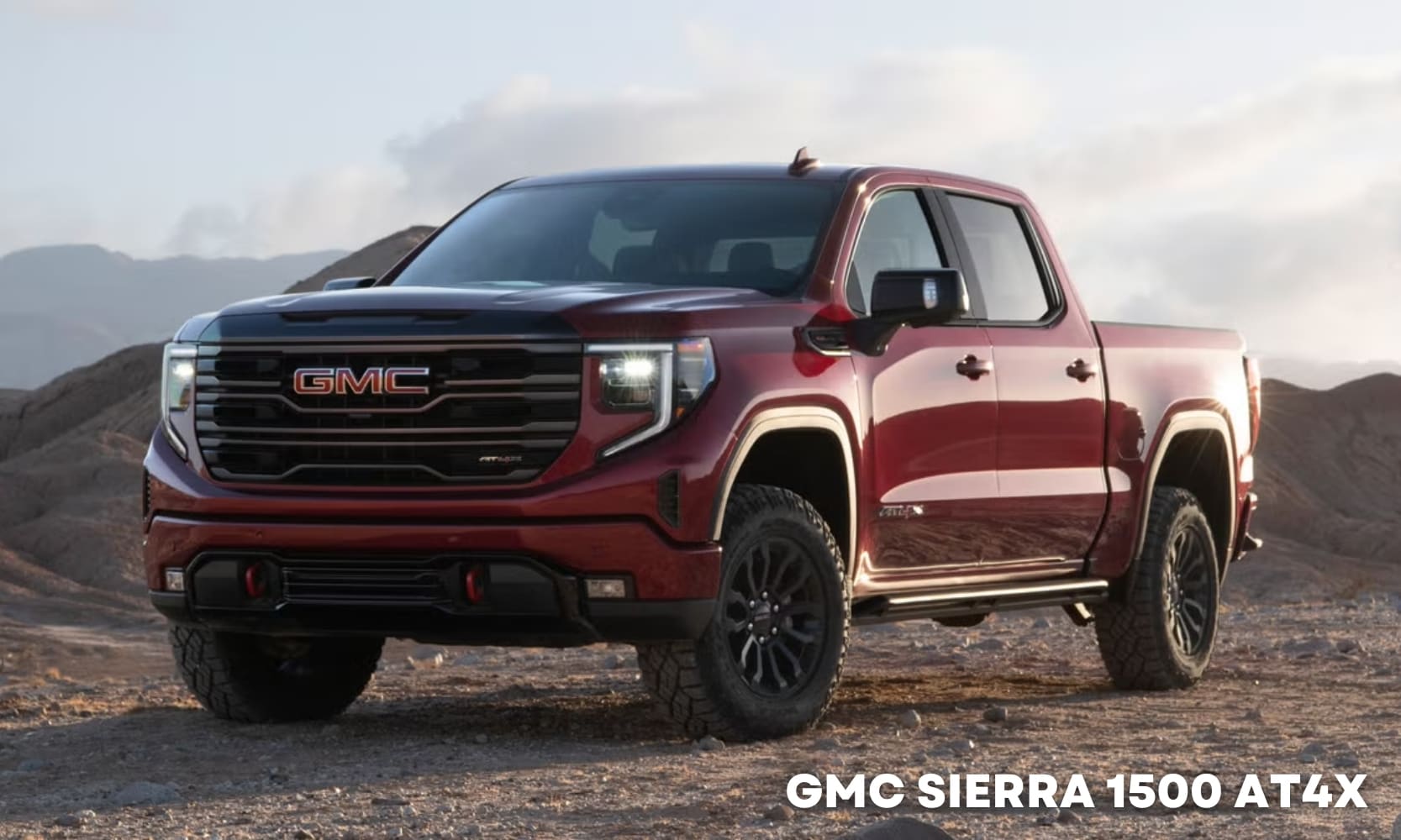 Image of a red 2025 GMC Sierra 1500 AT4X parked on a rocky dirt road with a mountain in the background