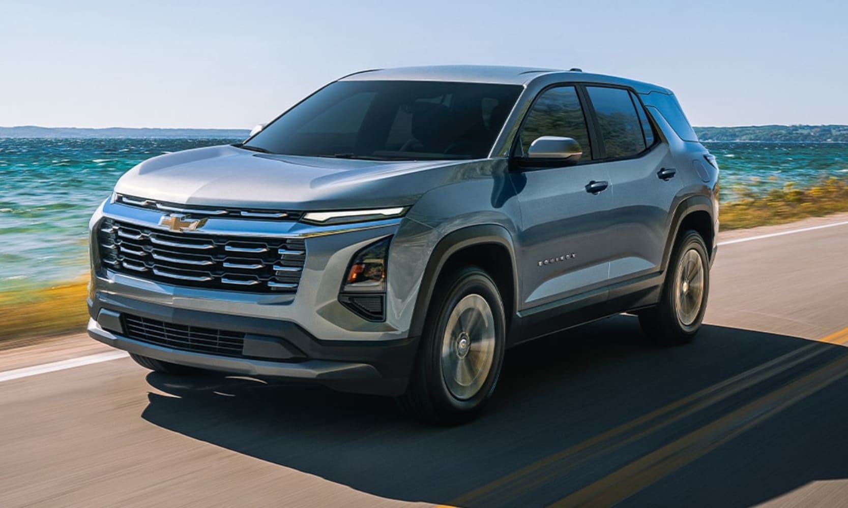 Exterior image of a silver 2026 Chevrolet Equinox LT driving on an open coastal freeway