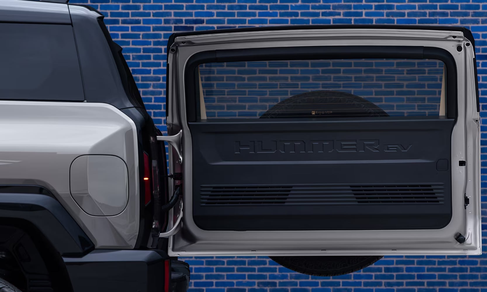 Closeup side image of a silver 2026 GMC Hummer EV SUV's power rear gate opened