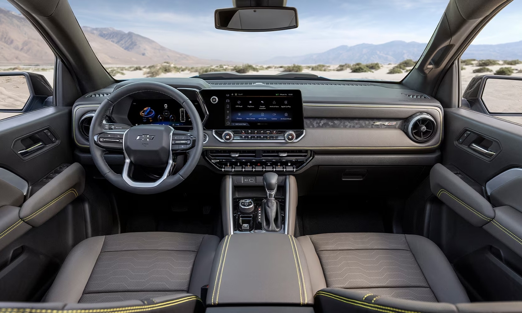 Interior image of a 2023 Chevy Colorado ZR2 front seats and dashboard with desert landscape views