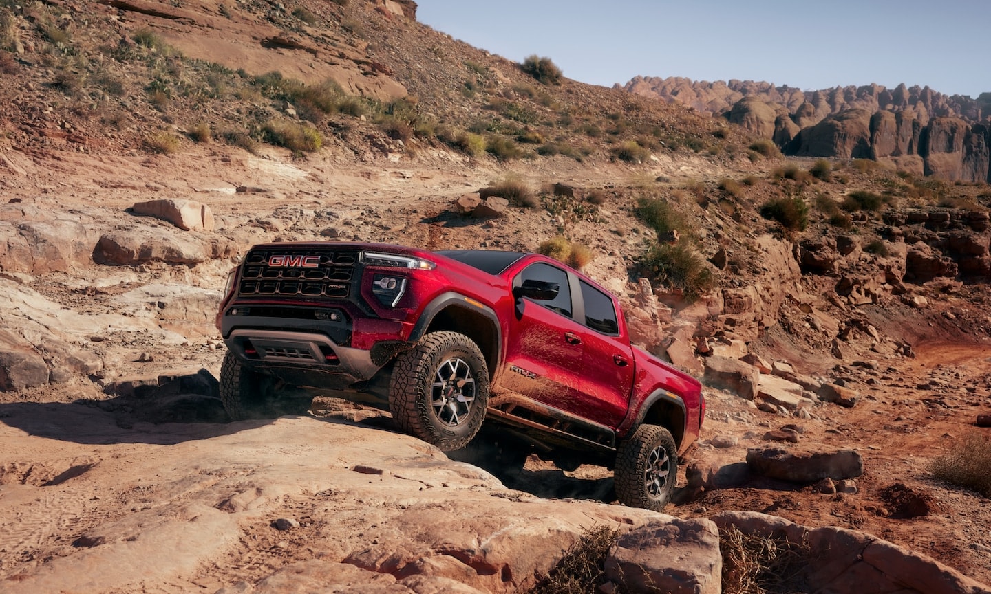 Exterior image of a red 2026 GMC Canyon AT4 off-roading up a steep rocky mountain incline