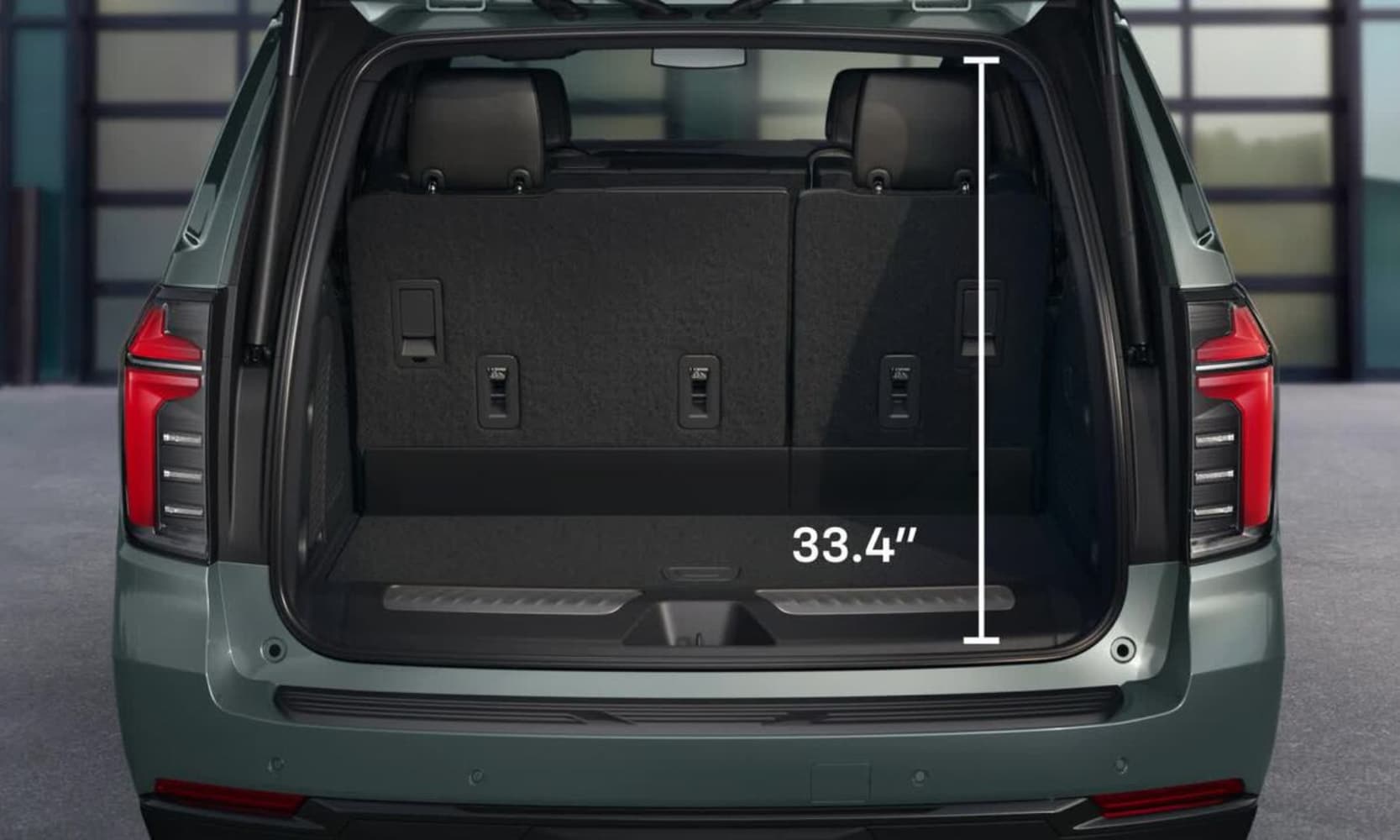 Exterior rear-view image of a light green 2026 Chevy Tahoe opened trunk and height specs displayed
