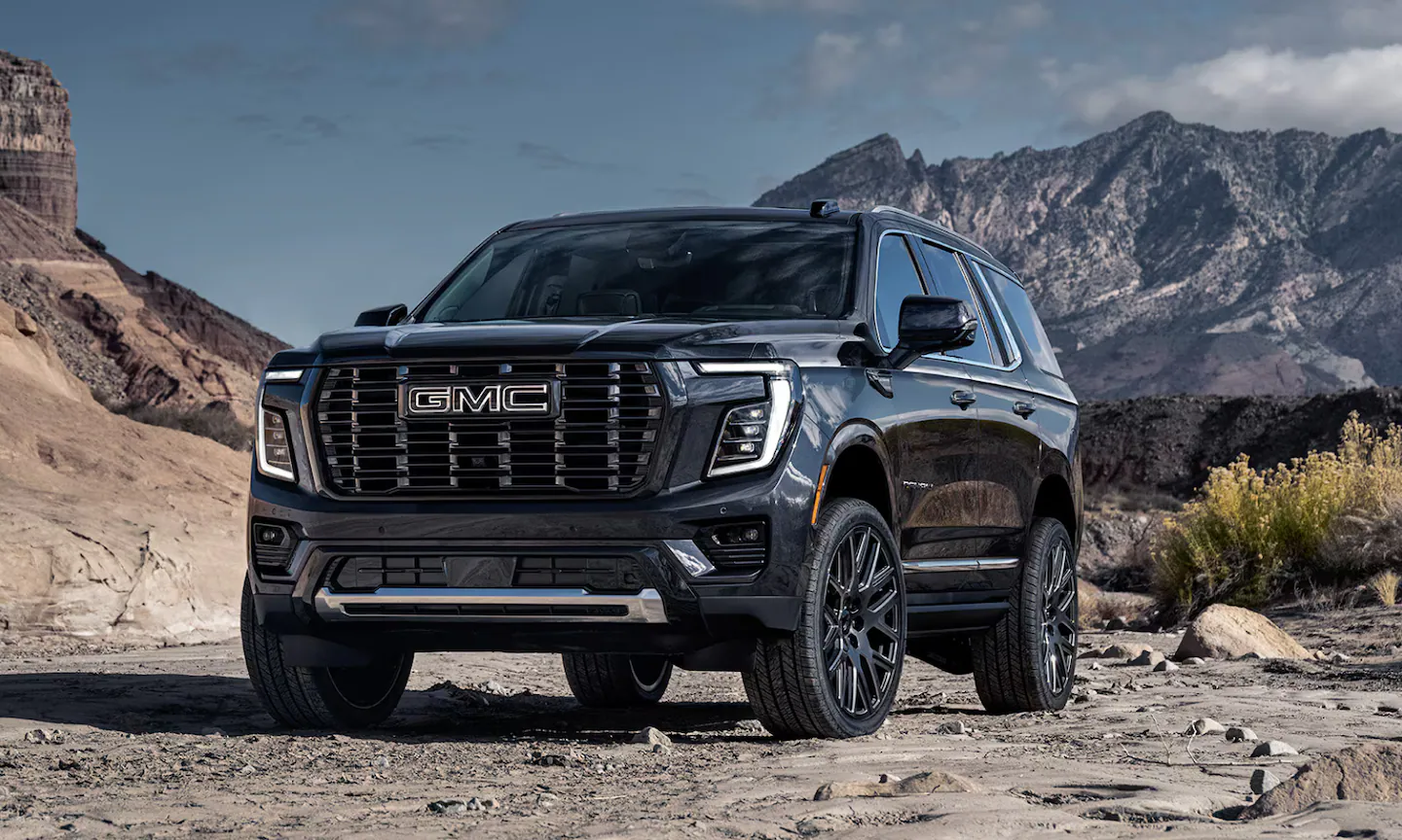 Exterior front image of a black 2026 GMC Yukon Denali Ultimate parked in a mountainous setting