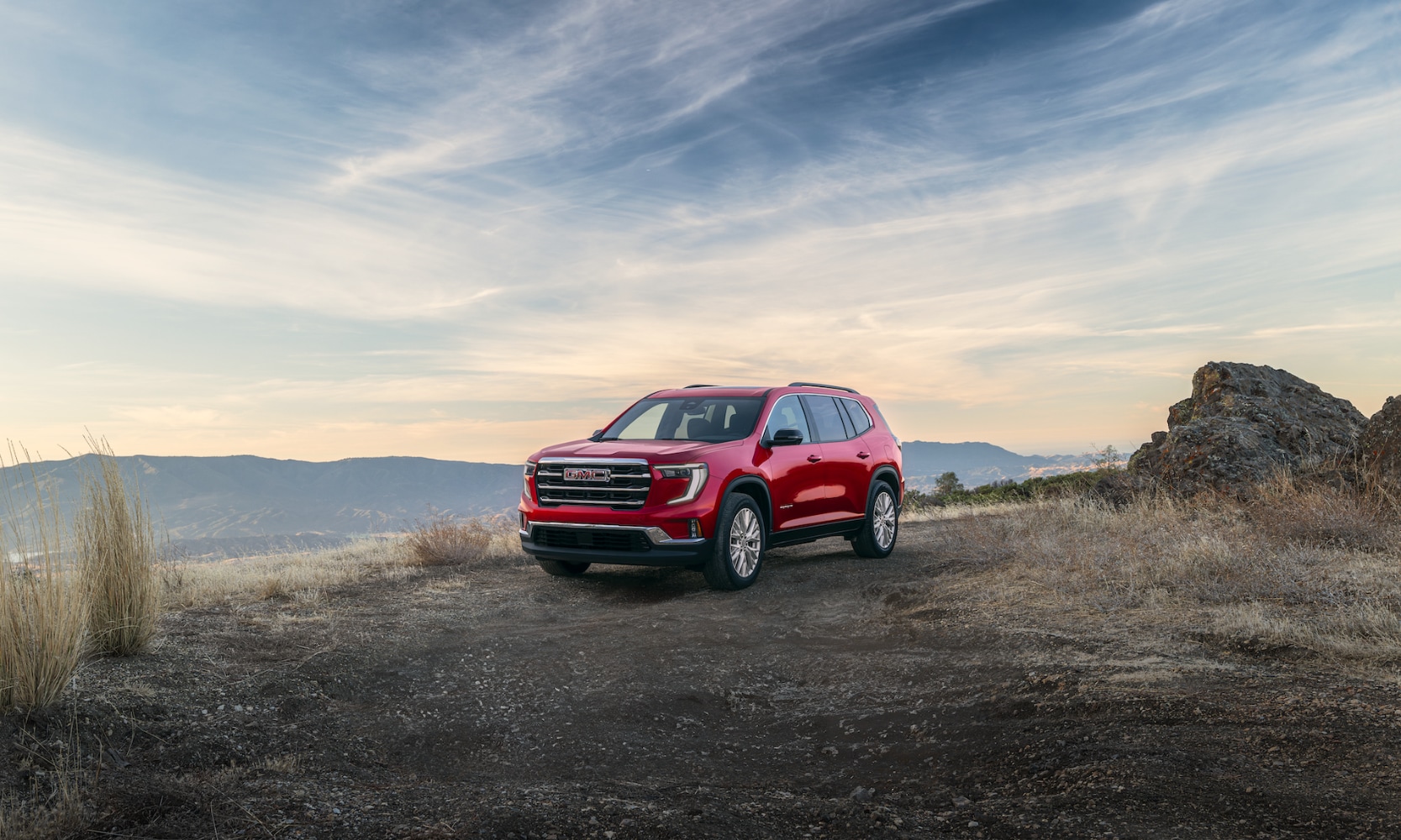 Exterior front angle image of a red 2024 GMC Terrain Elevation parked on a waterfront cliff