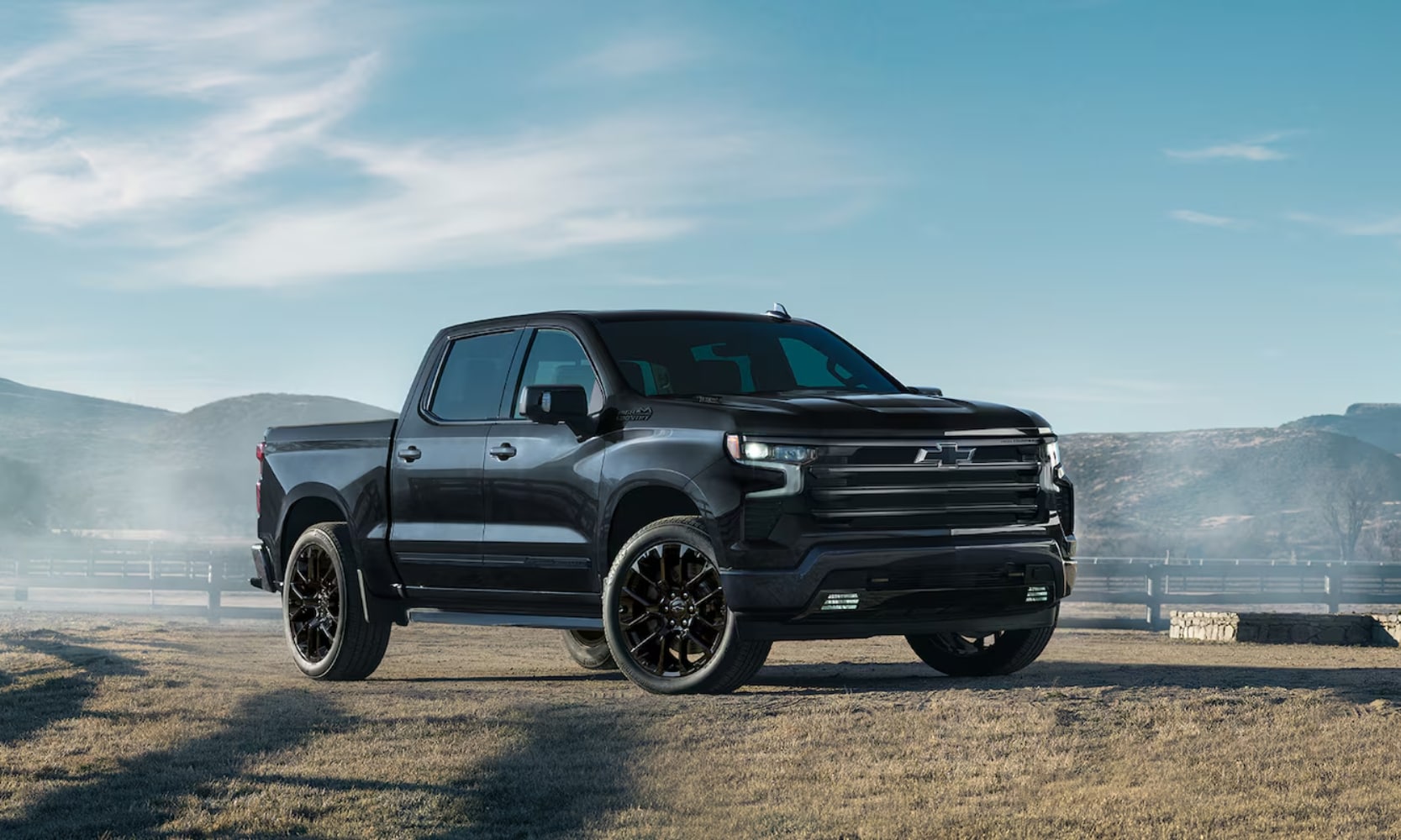 Exterior side angle image of a black 2025 Chevy Silverado High Country parked in a farm landscape