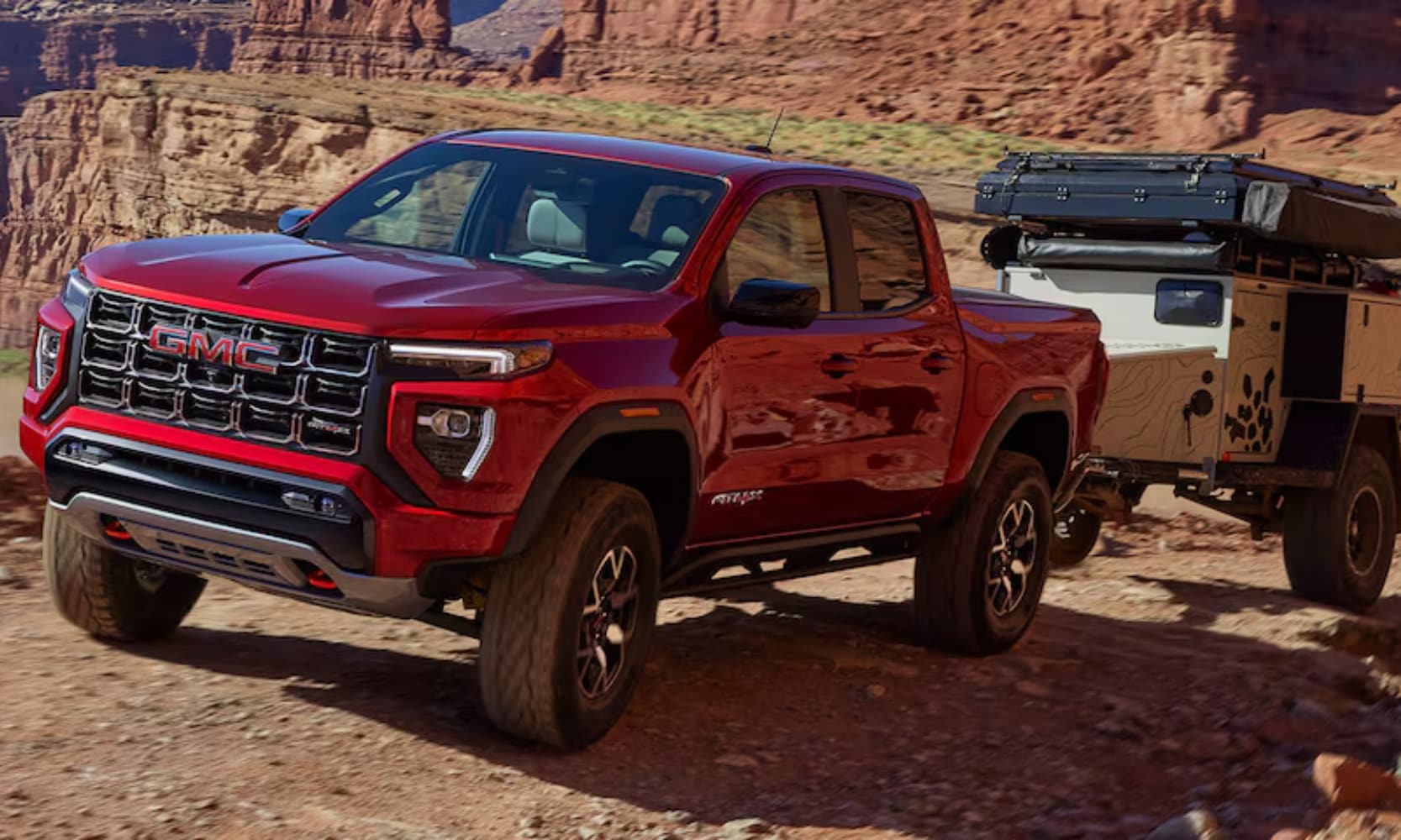 image of a red GMC 2024 Canyon Elevation towing a camper up a mountain