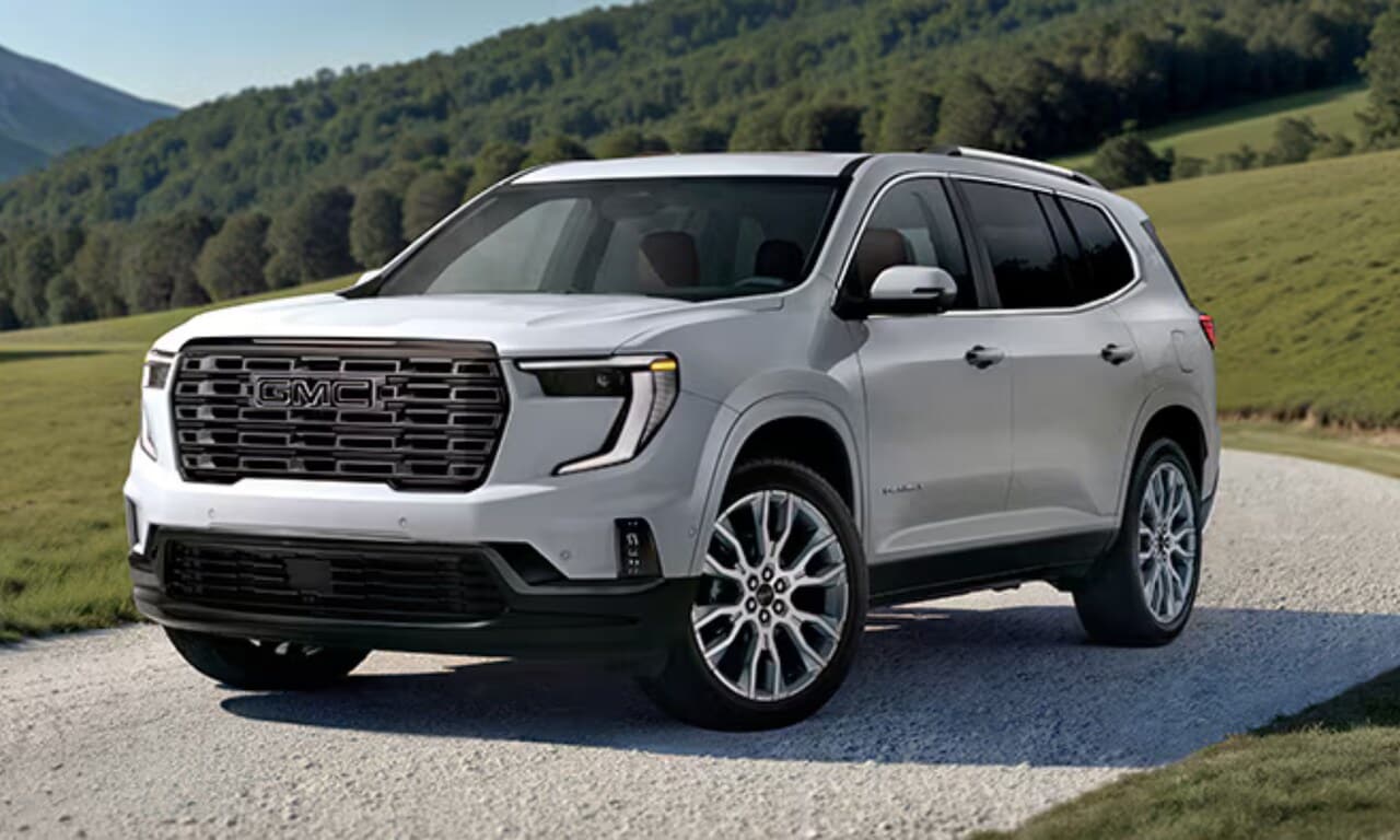 2Exterior image of a white 2026 GMC Acadia Denali parked in a grassy hill setting