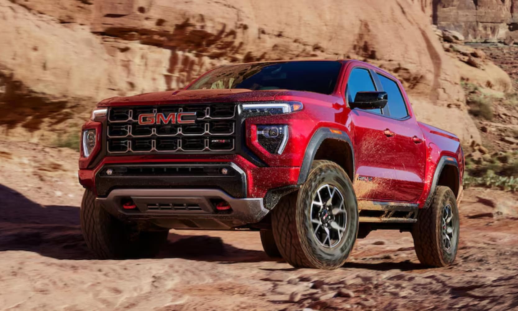 image of a red 2024 GMC Canyon AT4X driving up a rugged mountain terrain