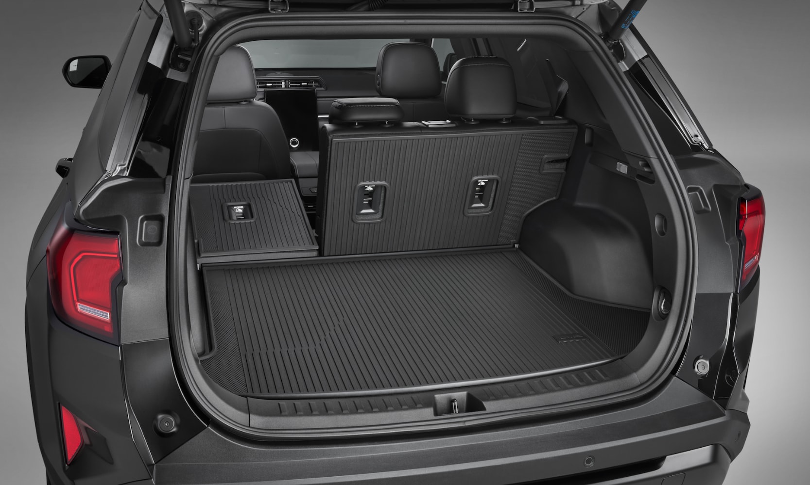 Exterior rear-view image of a black 2025 GMC Terrain open trunk and a rear seat folded down