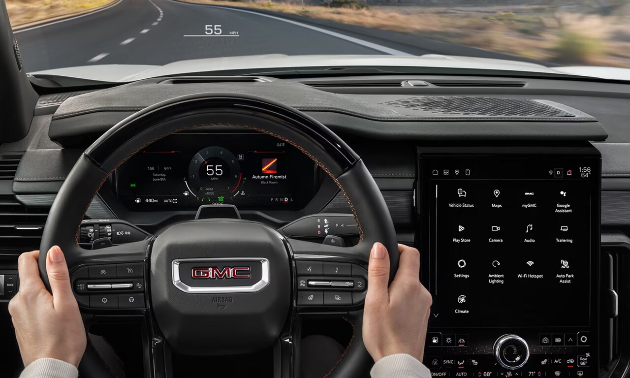 Interior image of a driver's hand on the steering wheel of the 2026 GMC Acadia and its safety features displayed