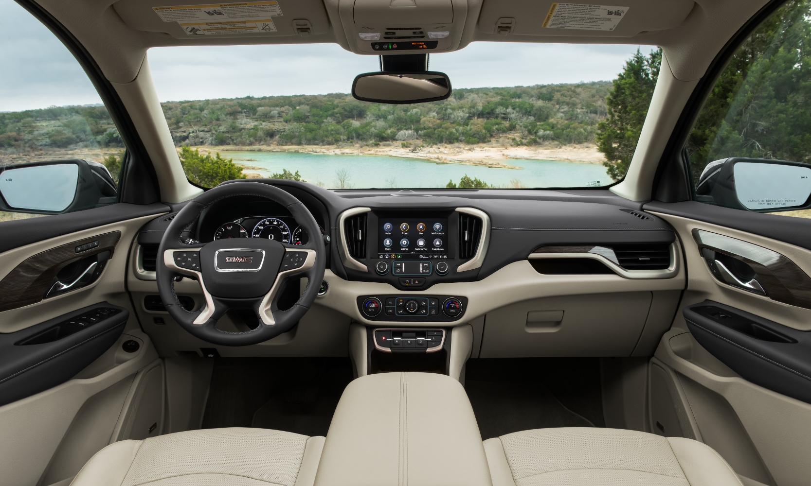 Interior image of a 2024 GMC Terrain Denali front seating area with white leather seats overlooking a lake