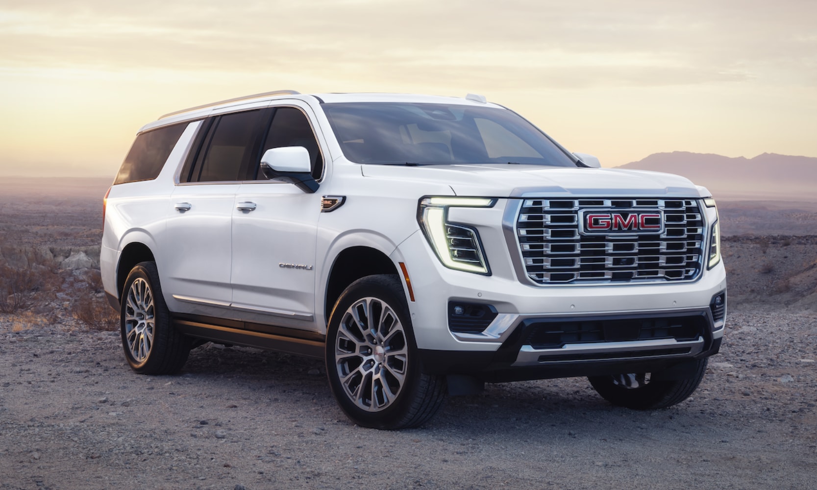 Closeup image of a white 2026 GMC Yukon parked in a mountainous setting