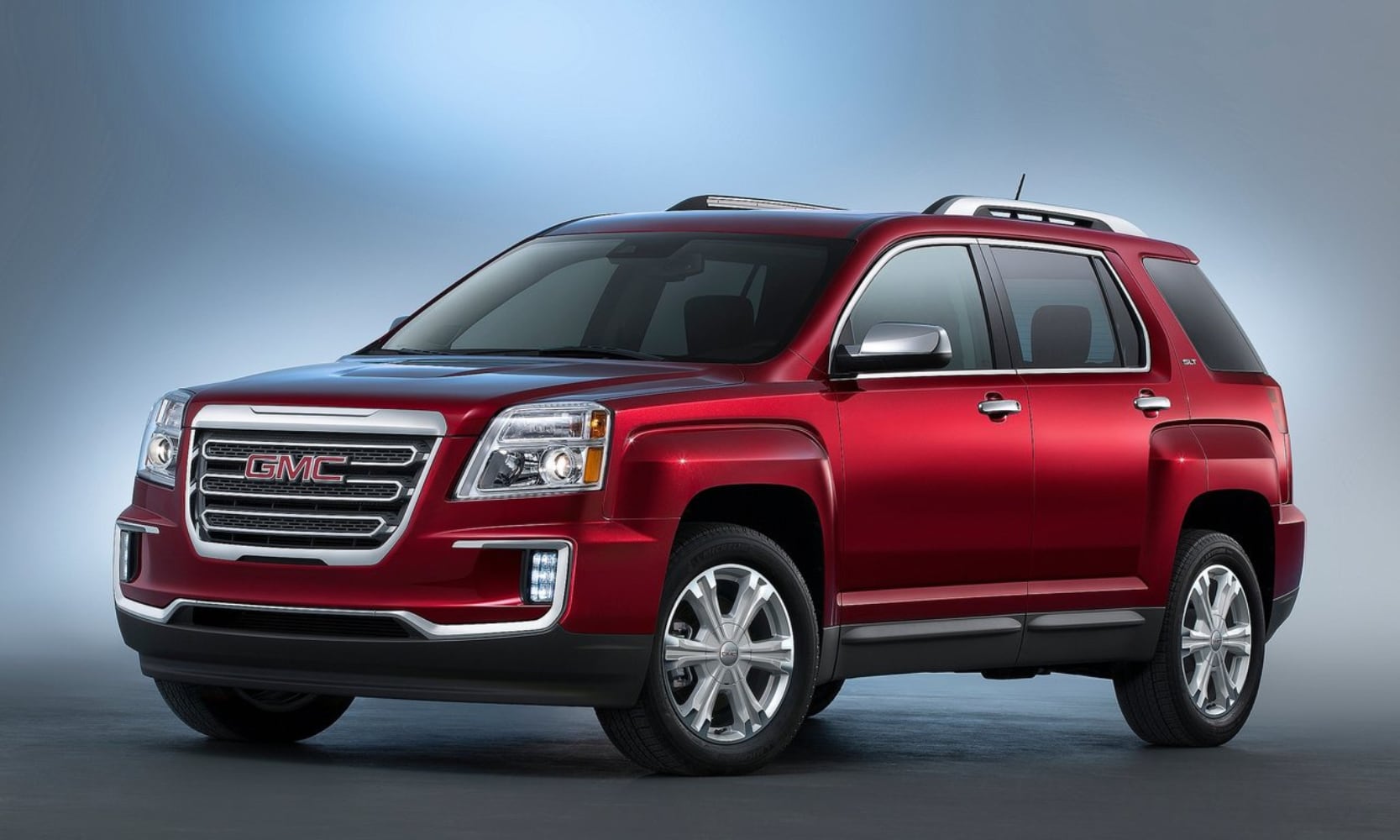 Exterior side angle image of a red 2016 GMC Terrain parked on a rendered faded background