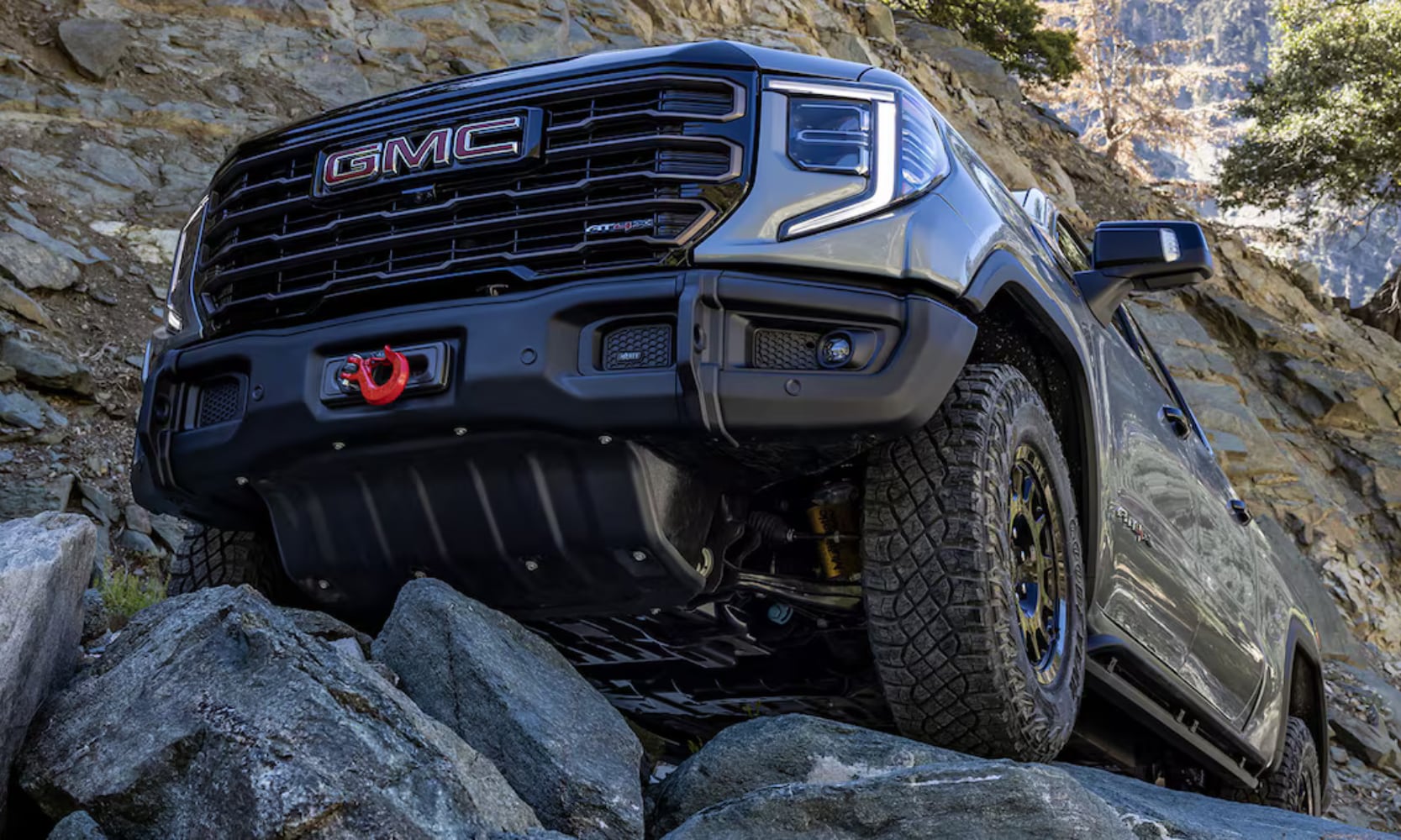 Close-up image of a gray 2025 GMC Sierra 1500 AT4X AEV Edition off-roading up a rocky cliff