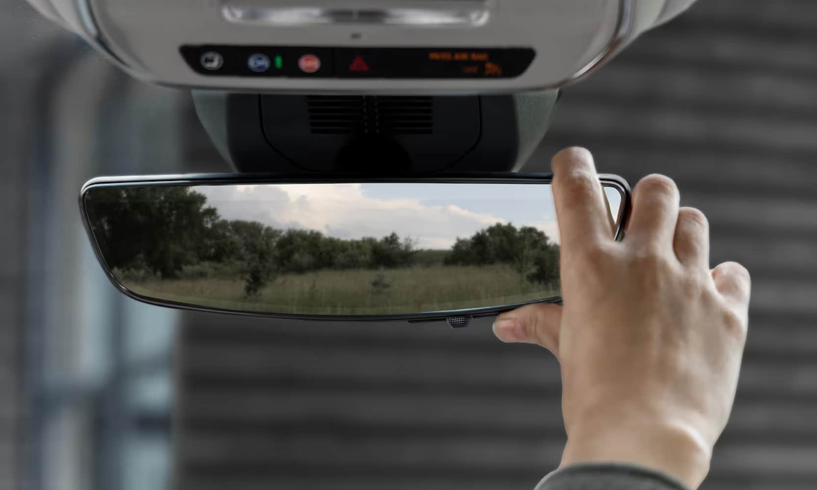 Close-up interior image of a person's hands adjusting the rear camera mirror on the 2025 GMC Terrain