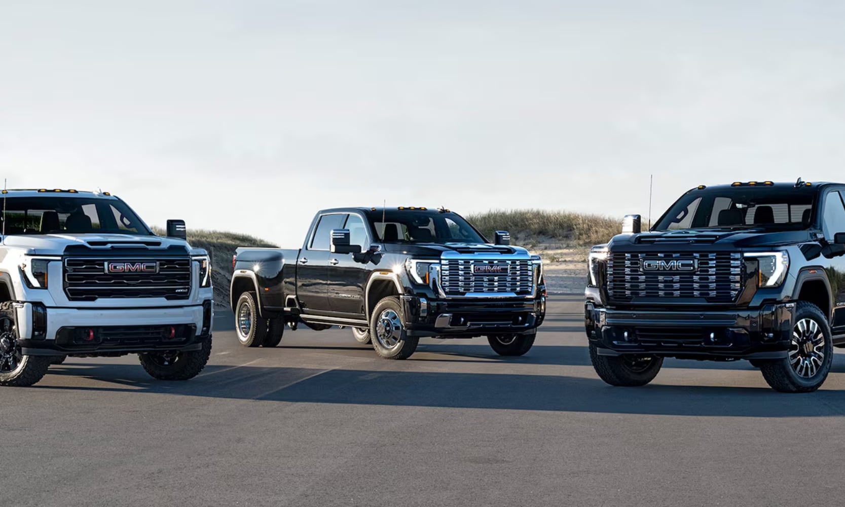Exterior front-view of three 2026 GMC Sierra HD models parked on a street