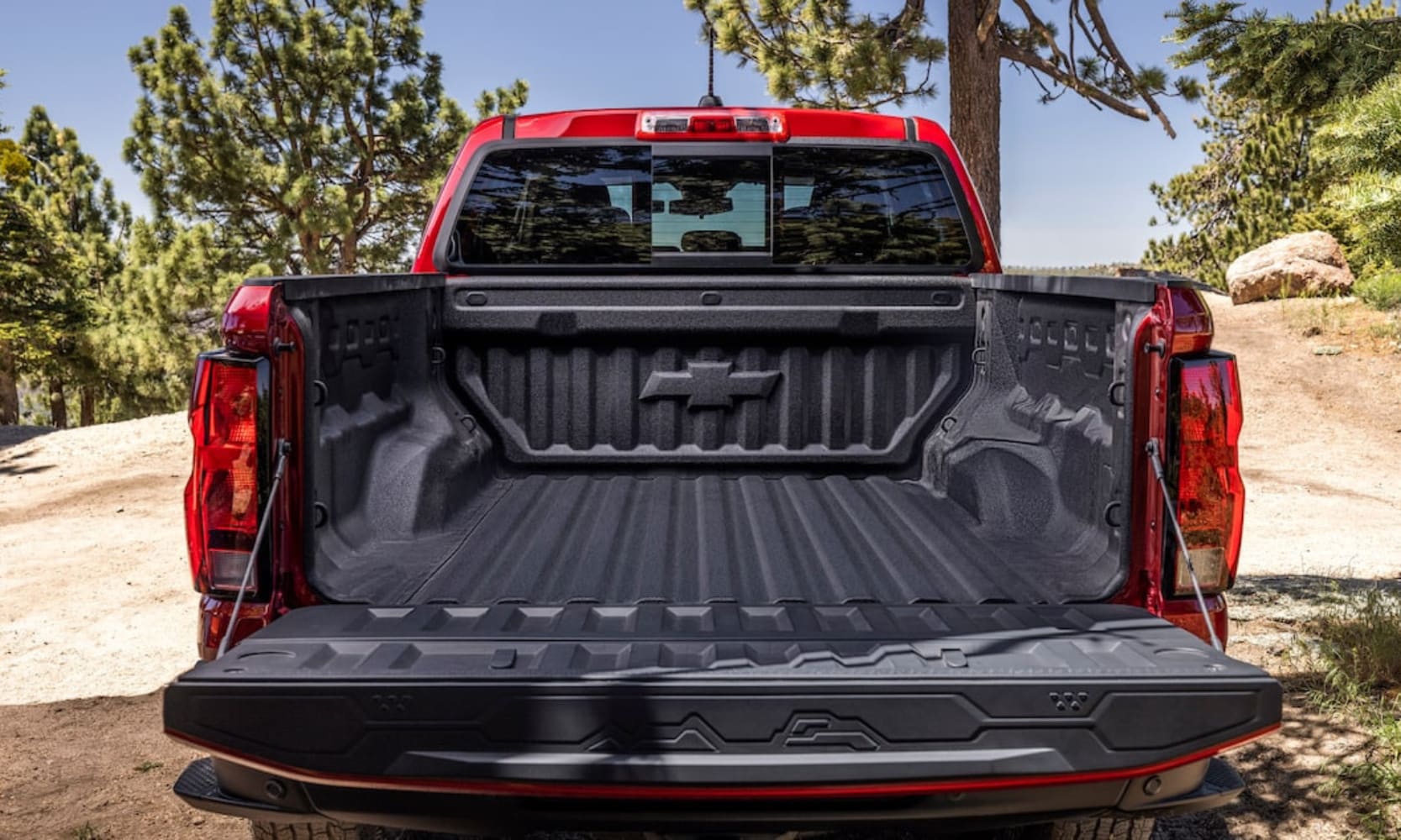 Close-up exterior image of a red 2026 Chevy Colorado opened cargo bed with equipment on it