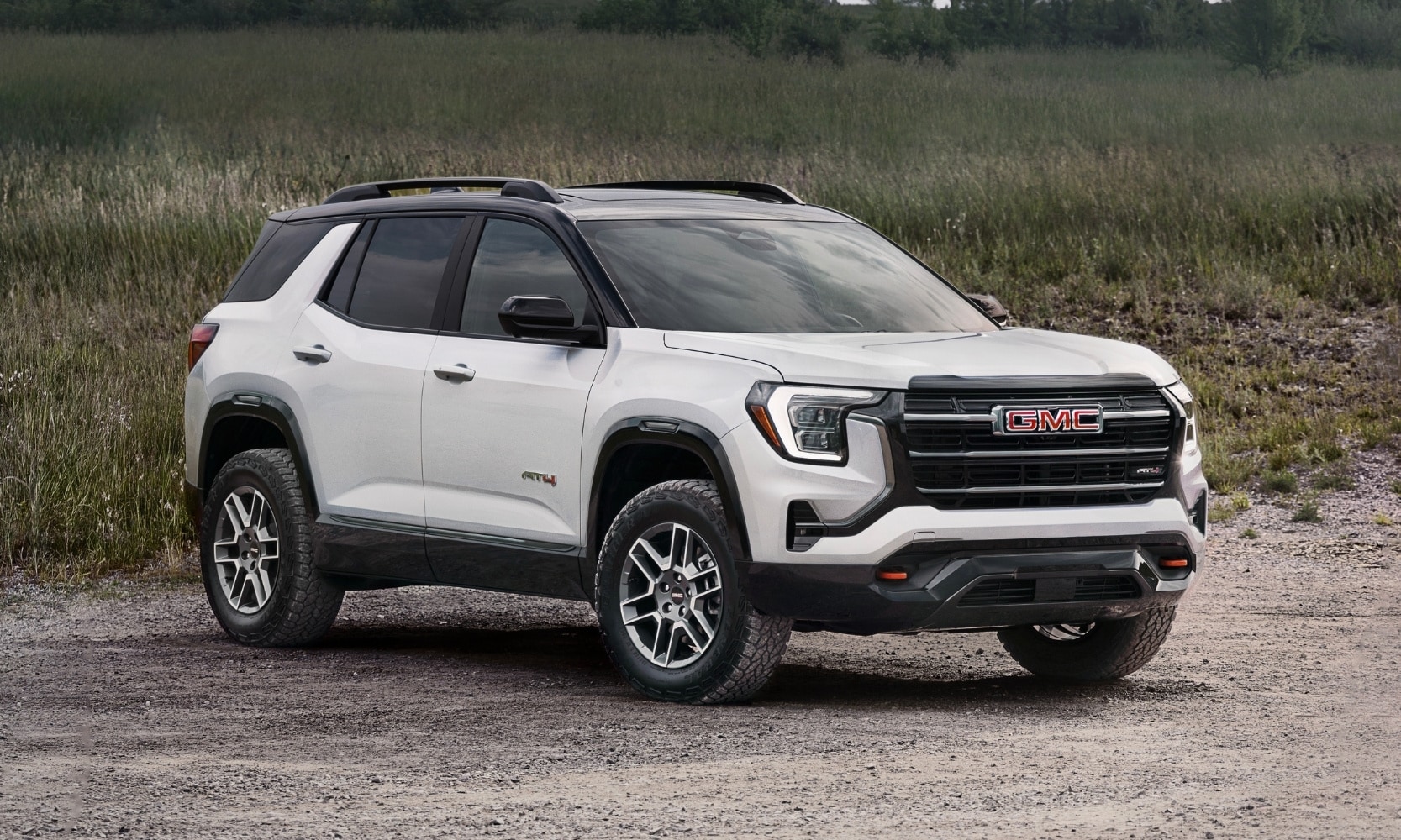 Exterior image of a white 2026 GMC Terrain AT4 parked in a sandy grassy field