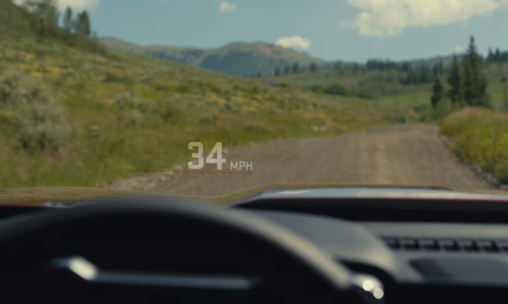 Closeup image of a 2026 GMC Canyon Denali's Head-Up Display on the windshield with forest mountain views