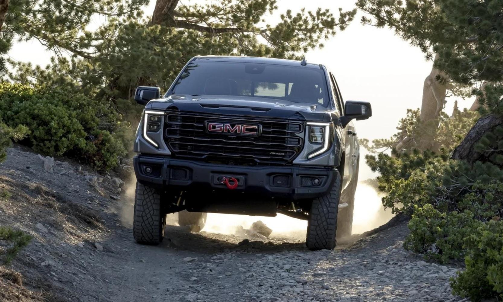 New 2023 GMC Sierra 1500 AT4X driving down a rocky path through a forest with ease