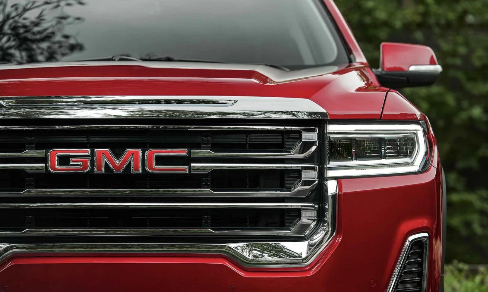 Up close view of the front of a 2022 GMC Acadia with shining led head lights