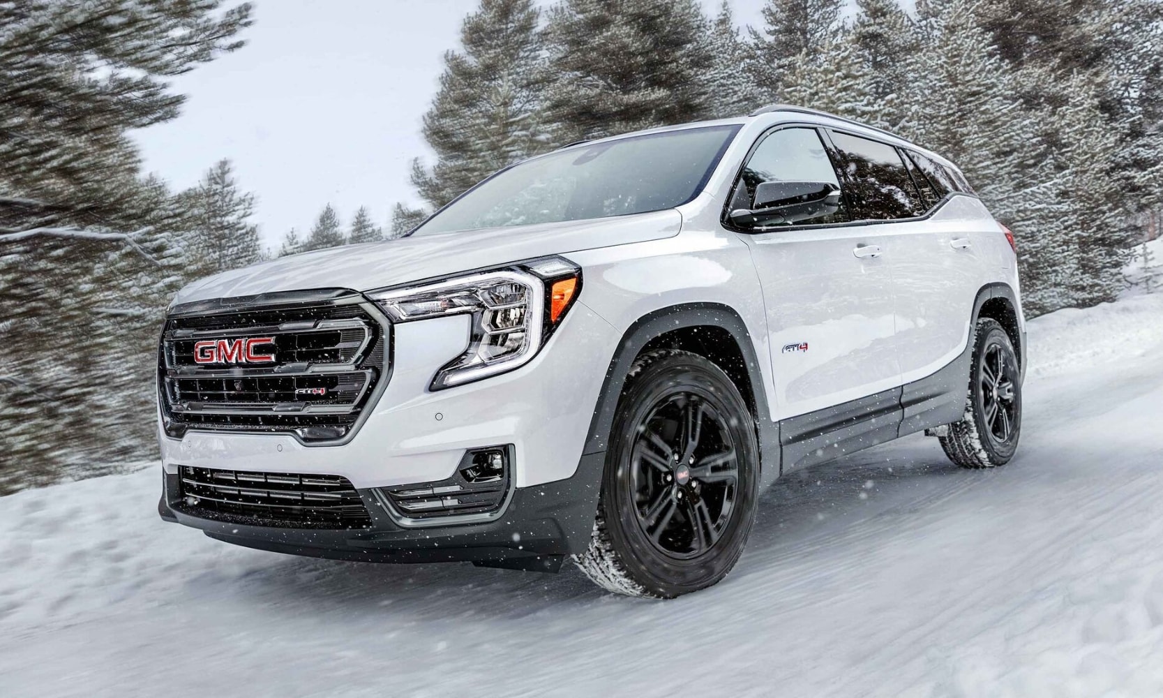 2023 GMC Terrain AT4 in white color driving through heavy snow on an off-road trail