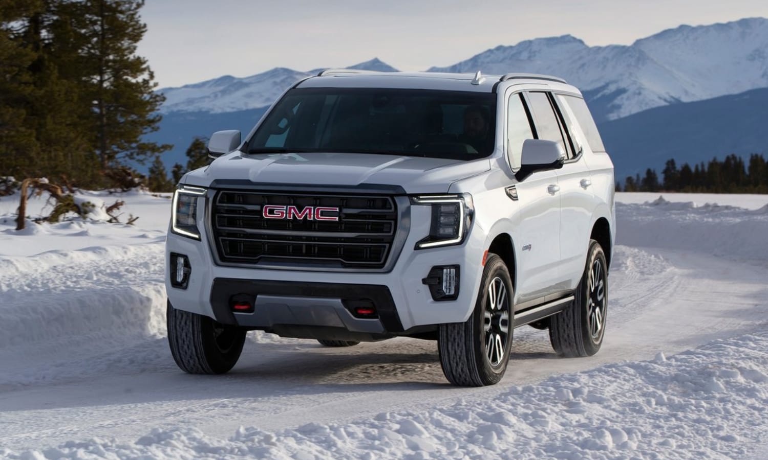 2022 GMC Yukon AT4 off-road focused model in white exterior color driving through snow in the mountains with ease