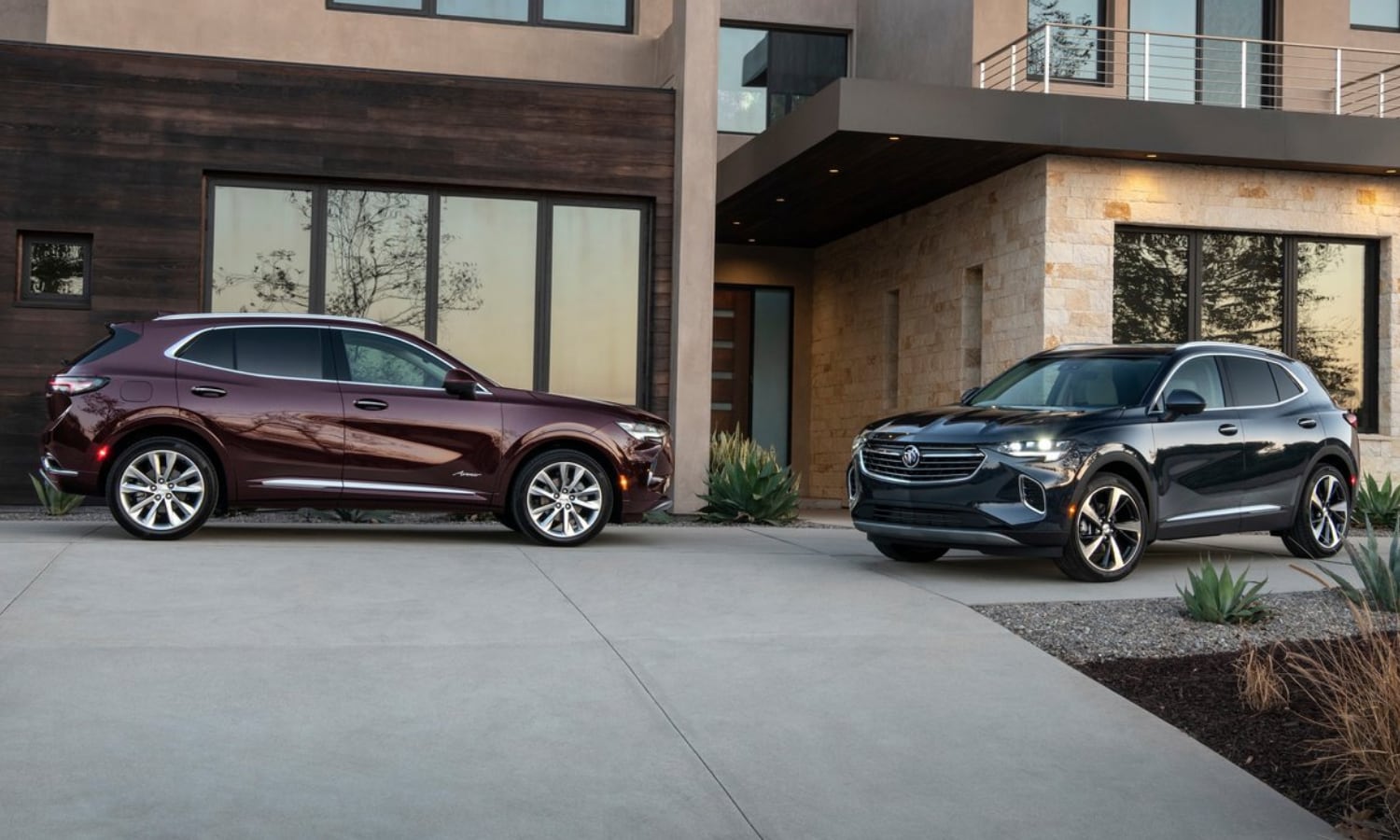 2022 Buick Envision Price & Configurations.png A new Buick Envision Essence SUV parked next to a Buick Envision Avenir SUV