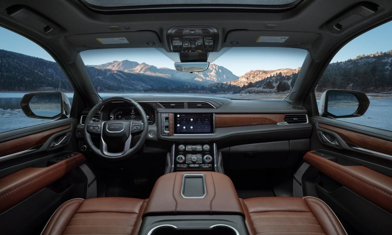 Front cabin view inside the interior of a 2023 GMC Yukon Denali with wood grain trim