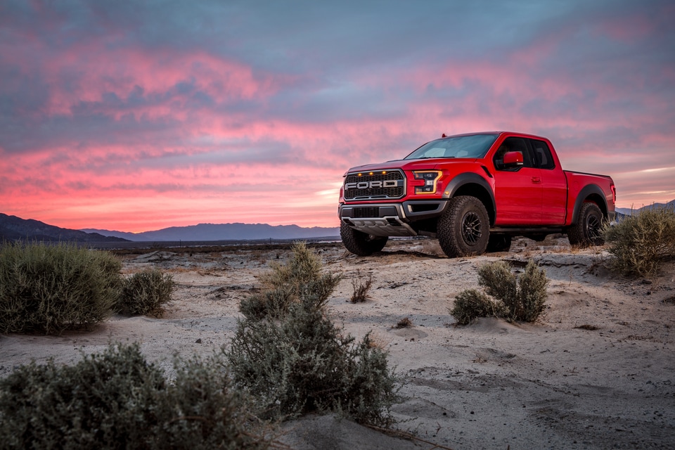 red Ford F-150 truck parked on desert sands