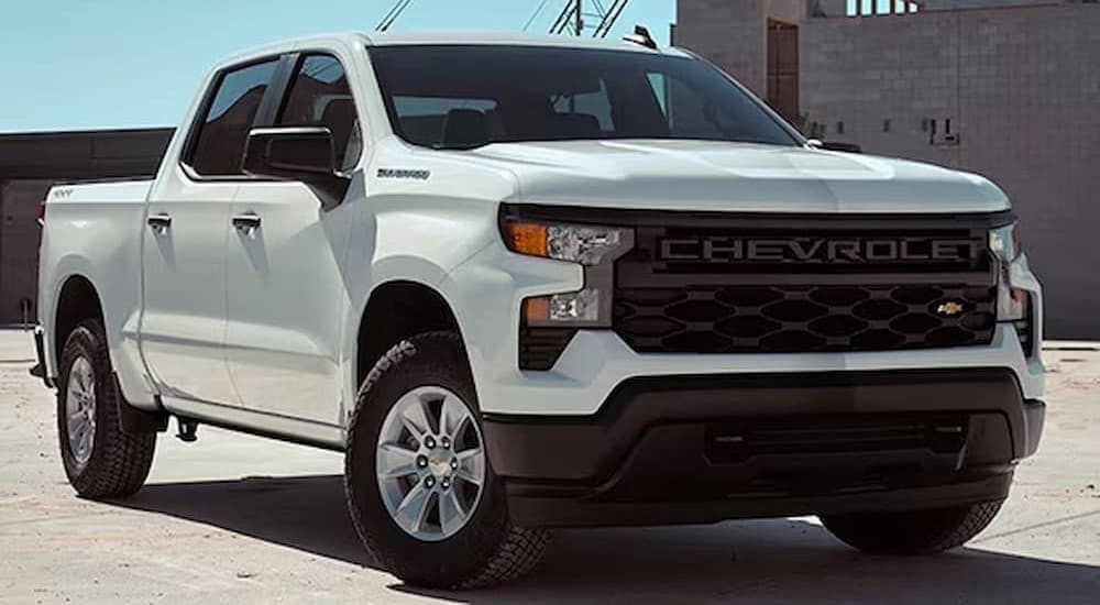 A popular Chevy Silverado for sale, a white 2024 Chevrolet Silverado 1500 WT, is shown parked near a building.