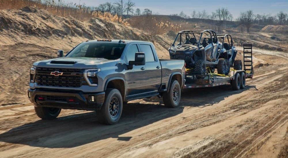 A gray 2024 Chevy Silverado 2500 HD ZR2 is shown towing a trailer.