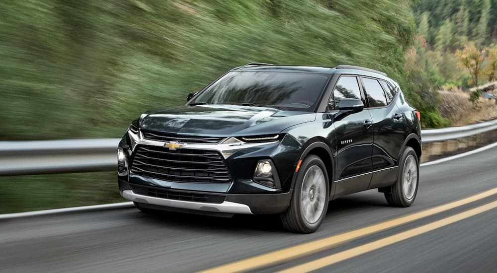 A black 2020 Chevy Blazer driving past trees on an open road.