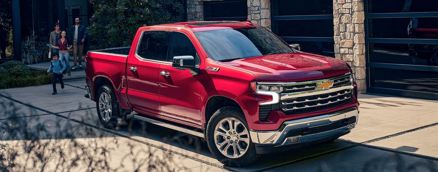 A family walks from their home to a red 2023 Chevy Silverado 1500 Z71 parked in the driveway.