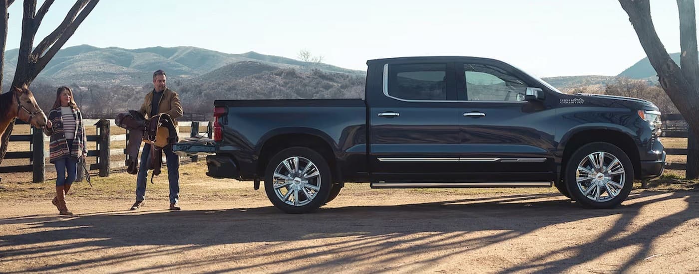  A popular Chevy Silverado 1500 for sale, a black 2024 Chevy Silverado 1500 High Country, is shown parked near a ranch.