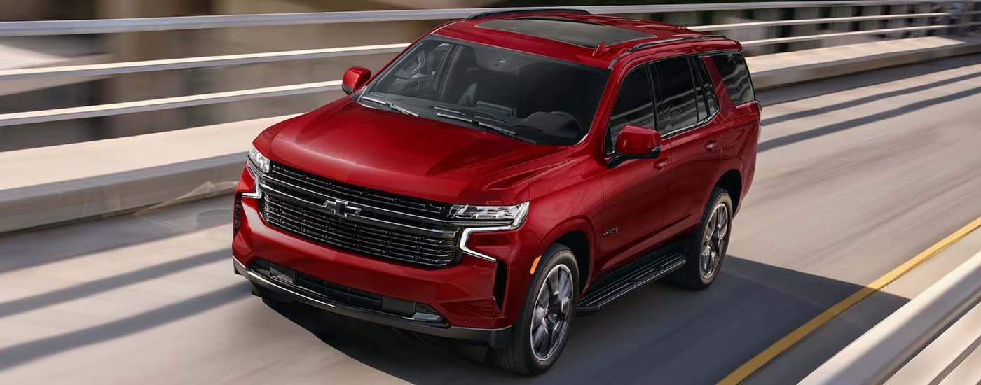 A red 2024 Chevy Tahoe RST is driving on a highway after viewing Chevy SUVs for sale near Upper Marlboro.